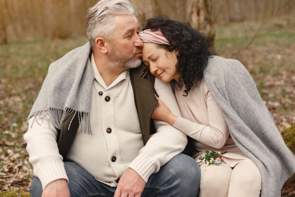 Senior couple enjoying a warm embrace in a serene autumn park, showcasing love and companionship.